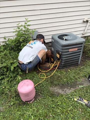 A technician servicing an air conditioner's refrigerant with gauges at a Niles, MI area home