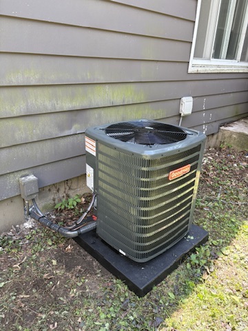 A Goodman AC condenser installed in a side yard at a Niles, MI area home